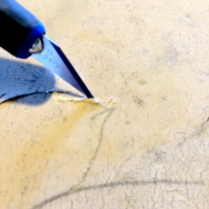 A blade with the sharp edge facing up will split the stencil without dulling the blade on the stone surface. 